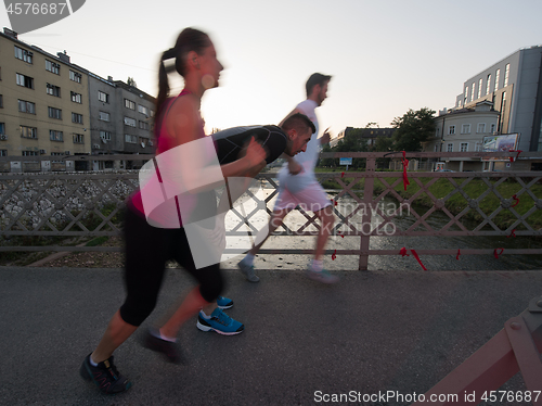 Image of group of young people jogging across the bridge