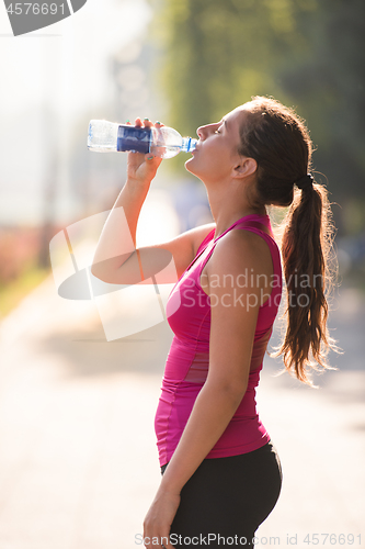 Image of woman drinking water from a bottle after jogging