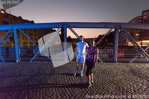 Image of couple jogging across the bridge in the city