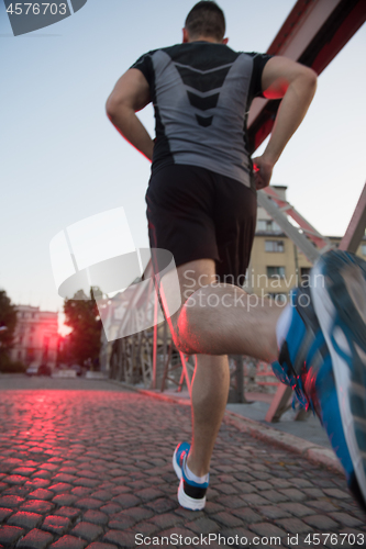 Image of man jogging across the bridge at sunny morning