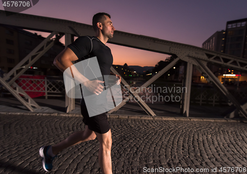 Image of man jogging across the bridge in the city