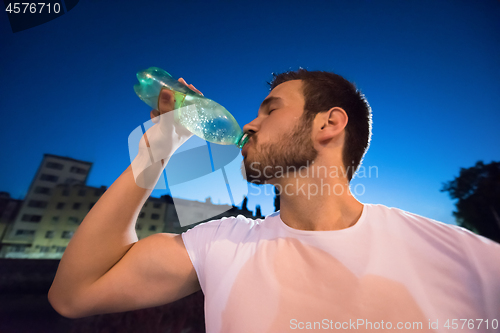 Image of man drinking water after running session