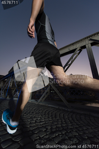 Image of man jogging across the bridge in the city