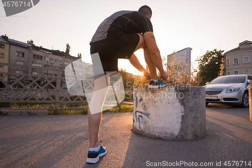 Image of man tying running shoes laces