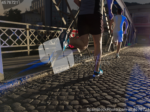 Image of young people jogging across the bridge