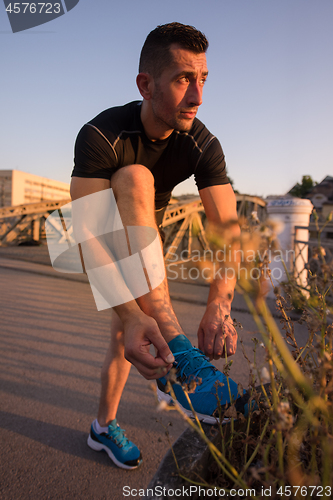 Image of man tying running shoes laces