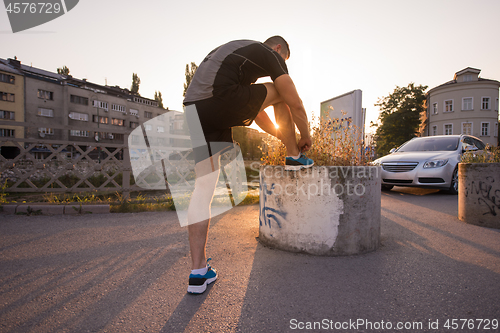 Image of man tying running shoes laces