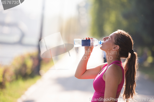 Image of woman drinking water from a bottle after jogging