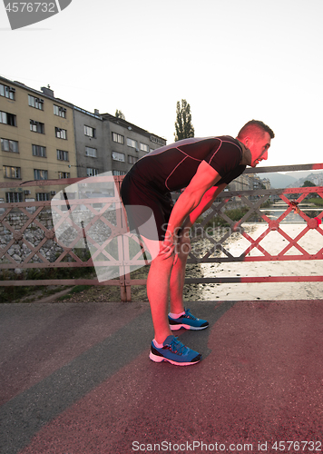 Image of man jogging across the bridge at sunny morning