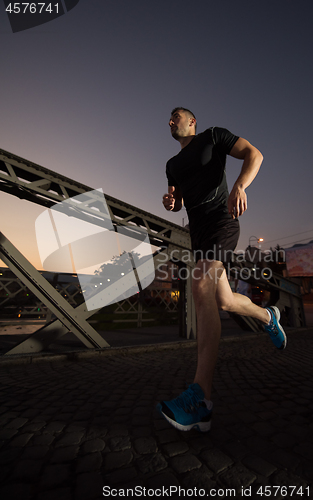 Image of man jogging across the bridge in the city