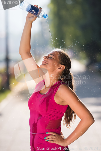 Image of woman pouring water from bottle on her head