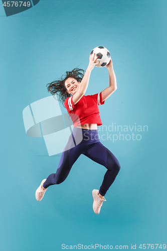 Image of Forward to the victory.The young woman as soccer football player jumping and kicking the ball at studio on pink