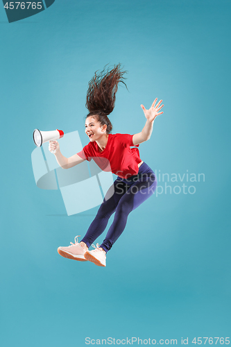 Image of Beautiful young woman jumping with megaphone isolated over red background