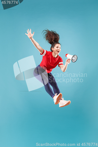 Image of Beautiful young woman jumping with megaphone isolated over red background