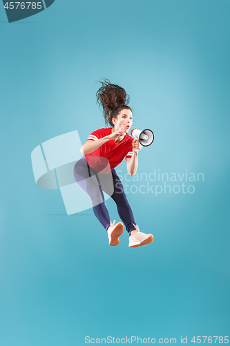 Image of Beautiful young woman jumping with megaphone isolated over red background