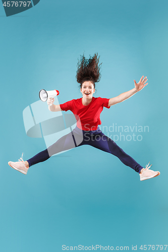 Image of Beautiful young woman jumping with megaphone isolated over red background