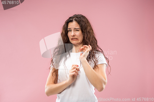 Image of Young woman with disgusted expression repulsing something, isolated on the pink