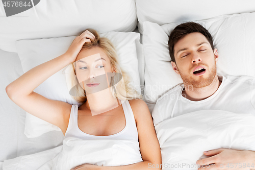 Image of unhappy woman in bed with snoring sleeping man