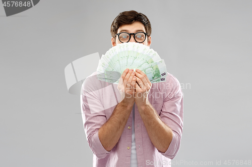 Image of happy young man in glasses with fan of euro money