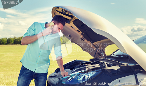 Image of man with broken car calling on smartphone