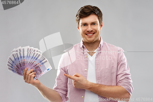 Image of smiling young man showing fan of euro money