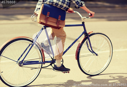 Image of young hipster man with bag riding fixed gear bike