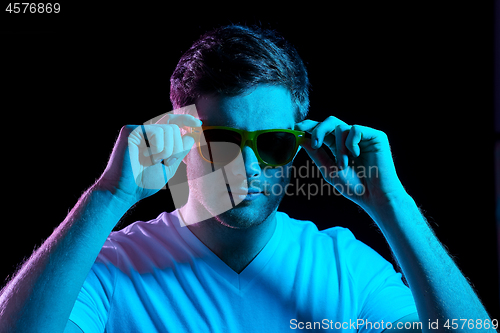 Image of man in sunglasses over ultra violet neon lights