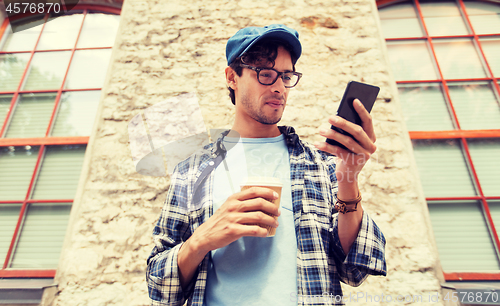 Image of man with smartphone drinking coffee on city street