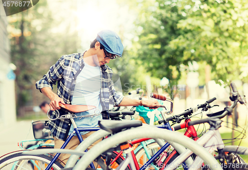 Image of hipster man parking fixed gear bike on city street