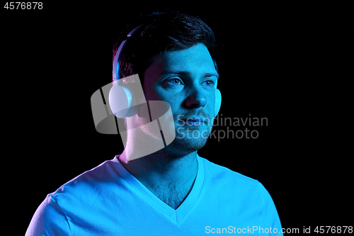 Image of man in headphones over neon lights of night club