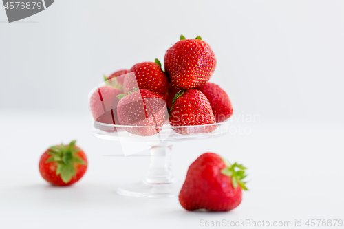 Image of strawberries on glass stand over white background