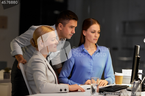 Image of business team with computer working late at office