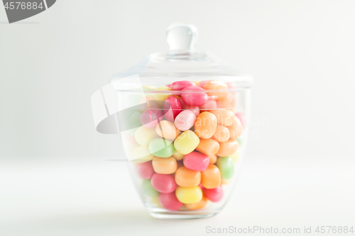 Image of glass jar with candy drops over white background