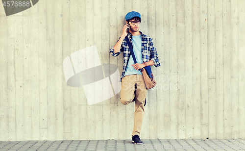 Image of man with bag calling on smartphone at street wall