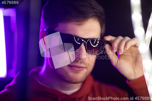 Image of man in sunglasses over ultra violet neon lights