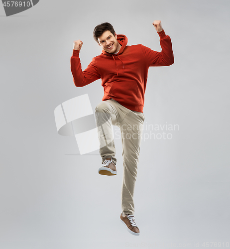 Image of man in hoodie jumping and celebrating success