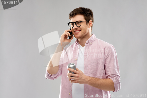 Image of young man in glasses with smartphone and drink