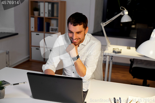 Image of businessman with laptop working at night office