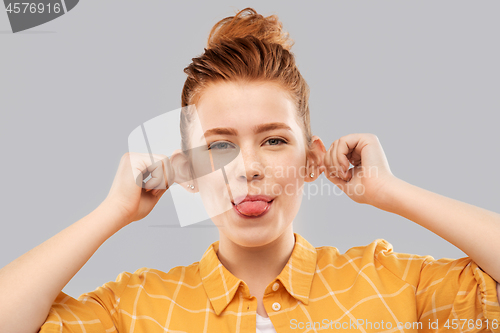 Image of smiling red haired teenage girl showing her tongue