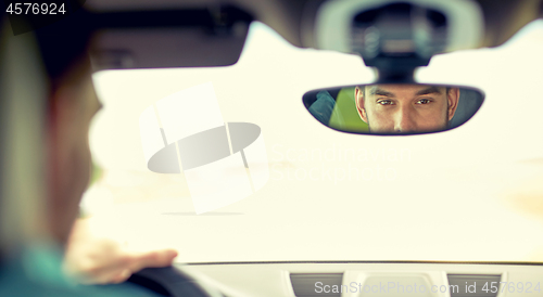 Image of rearview mirror reflection of man driving car