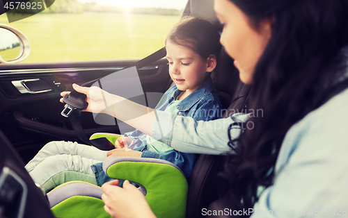 Image of happy woman fastening child with seat belt in car