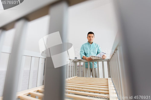 Image of father with manual assembling baby bed at home