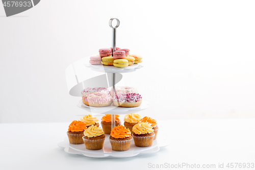 Image of glazed donuts, cupcakes and macarons on stand