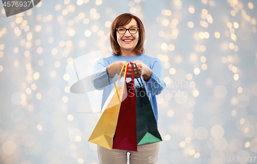 Image of senior woman with shopping bags over grey