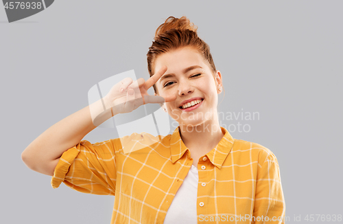 Image of smiling red haired teenage girl showing peace