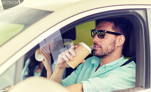 Image of happy man and woman driving in car with coffee