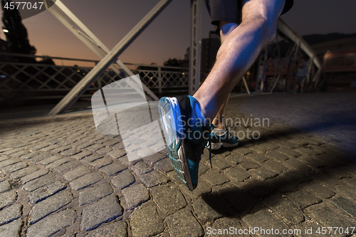 Image of man jogging across the bridge in the city