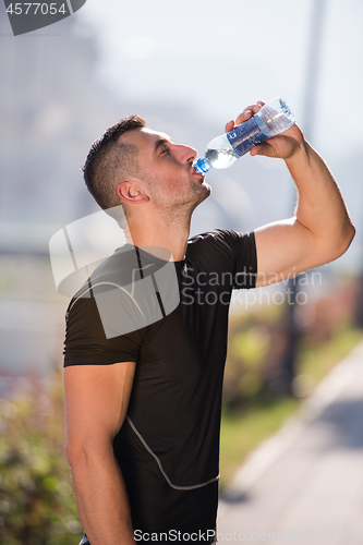 Image of man drinking water from a bottle after jogging