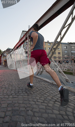 Image of man jogging across the bridge at sunny morning