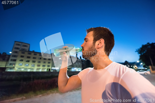 Image of man drinking water after running session